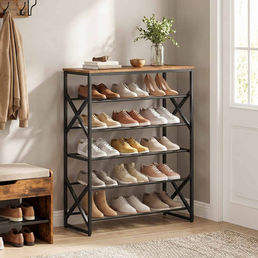 Large 5-tier industrial shoe rack organiser placed in a warm entryway filled with leather boots, sneakers, and a flower vase on top.