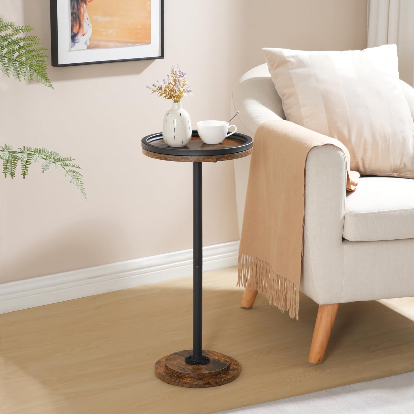 Small industrial round coffee table styled next to a lounge couch holding a coffee cup and vase.