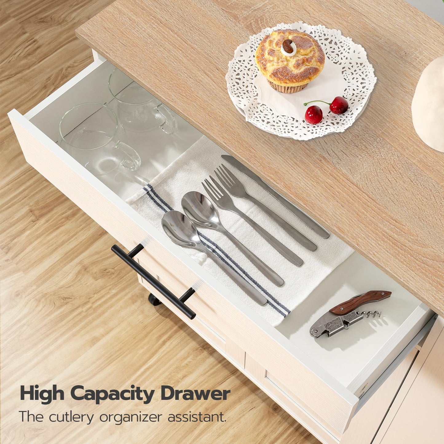 Open kitchen drawer with cutlery and a cupcake on a wooden surface