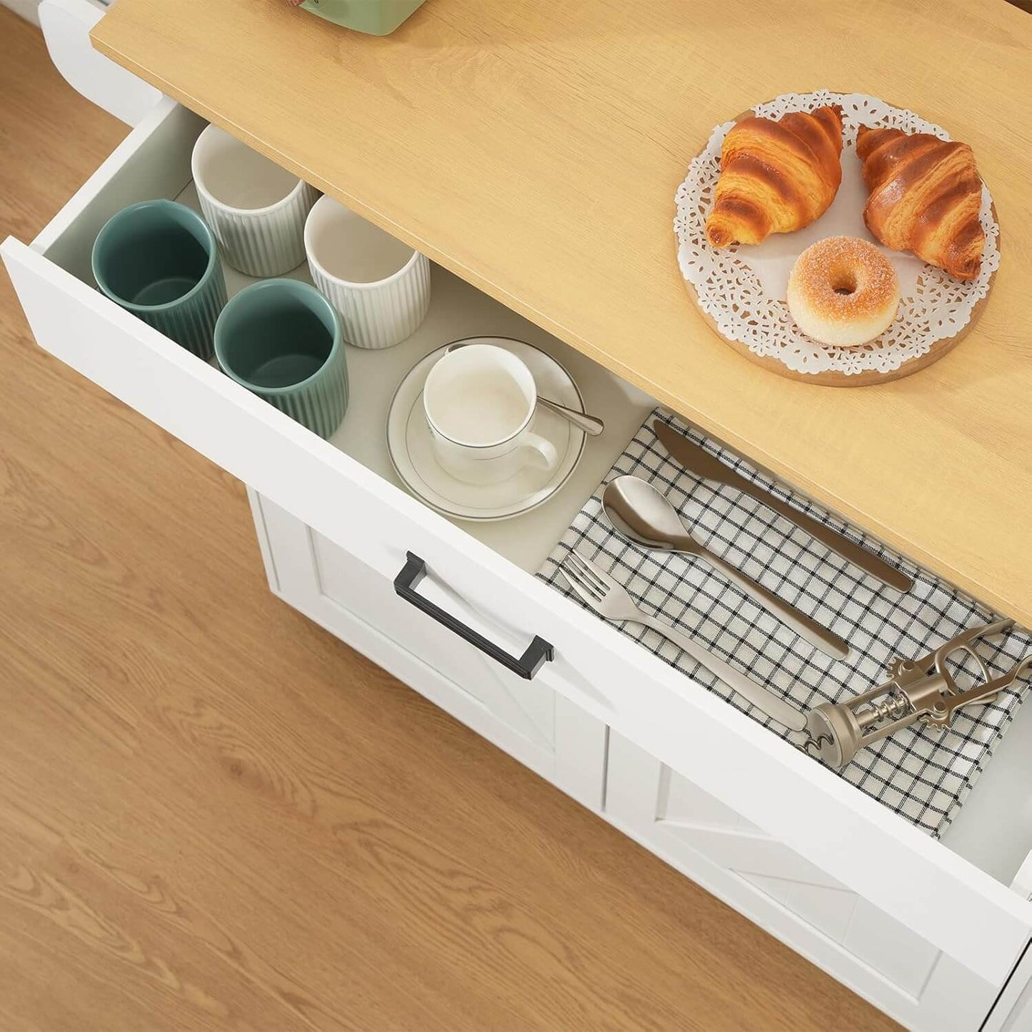 Open kitchen drawer with croissants on a plate above it