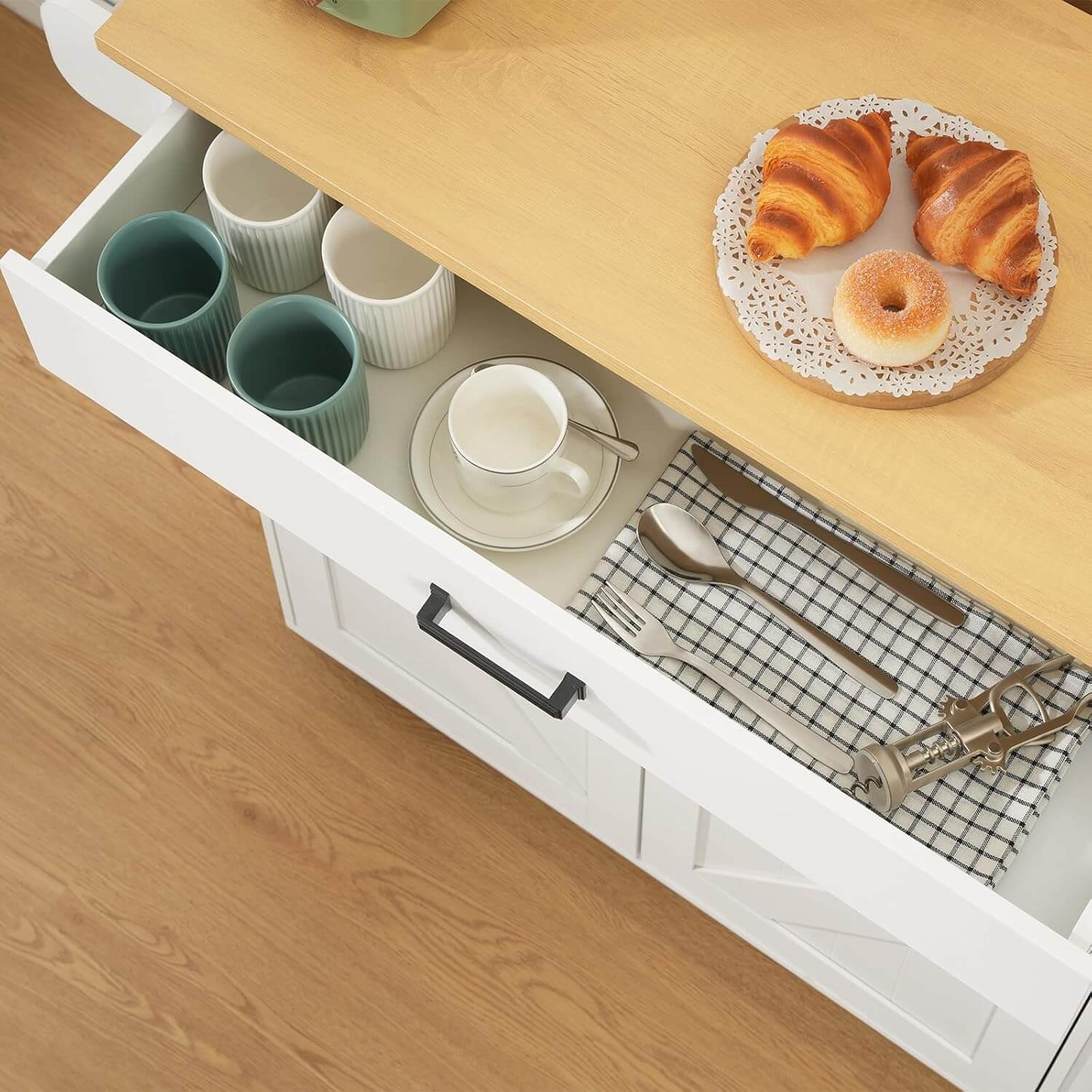 Open kitchen drawer with croissants on a plate above it