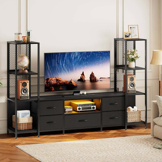 A black metal and wood TV stand console with integrated drawers and open shelving, shown in a styled living room setting with a television, speakers, and decorative items.