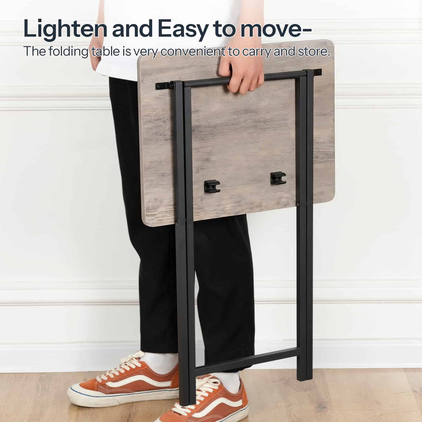 A person holding the lightweight, fully folded flat wooden side table with one hand, demonstrating easy moving.