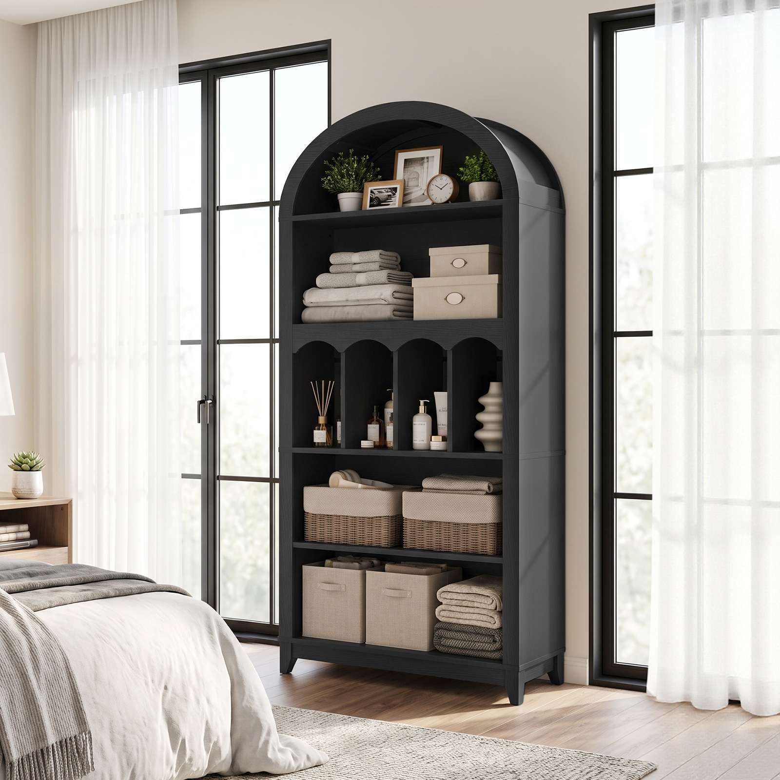 Bright bedroom interior scene showing the minimalist tall black bookcase tower positioned gracefully next to a sliding glass door.