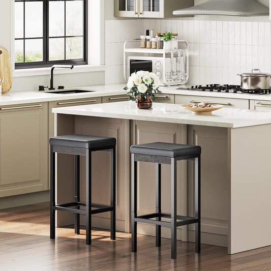 Set of 2 modern black bar stools with thick padded seats placed next to a white kitchen island.