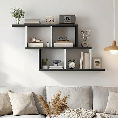 Modern geometric black and white floating shelves mounted on a wall displaying books and home decor.