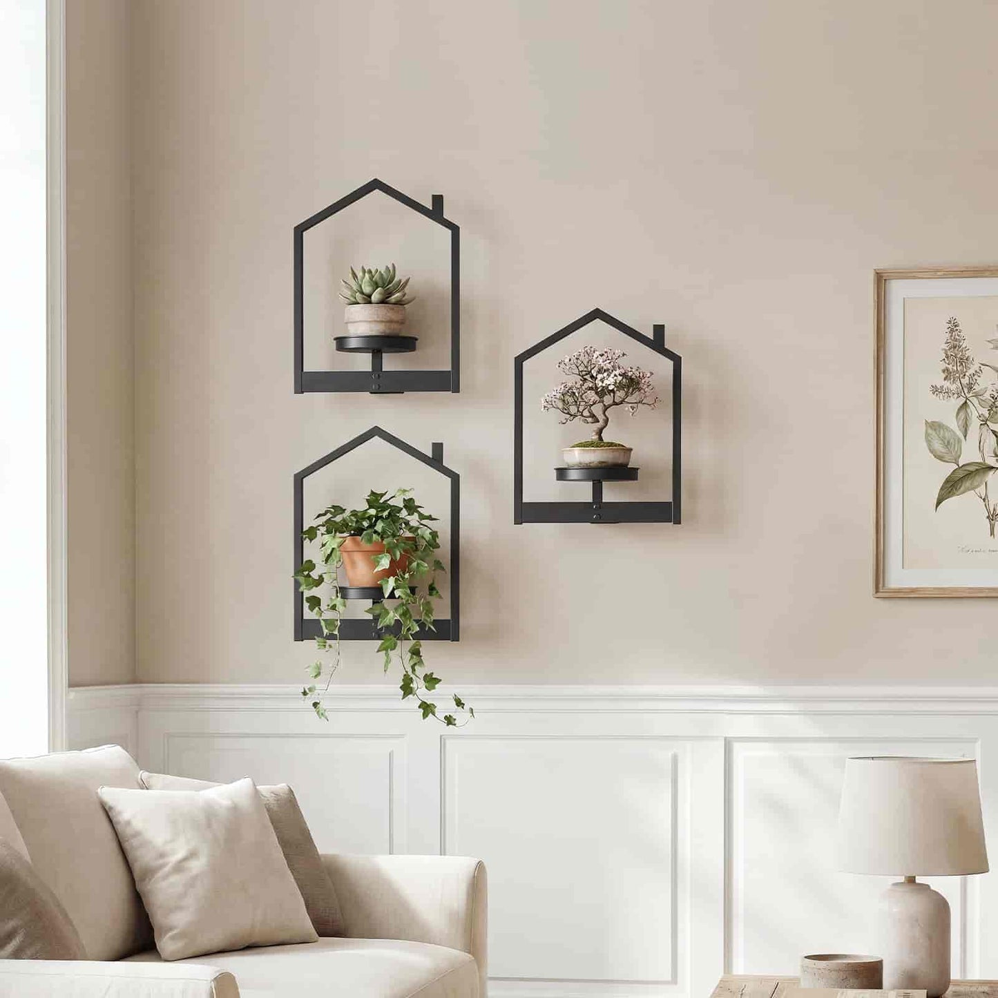 Symmetrical arrangement of three house-shaped wall shelves with cascading plants above a light grey living room sofa.