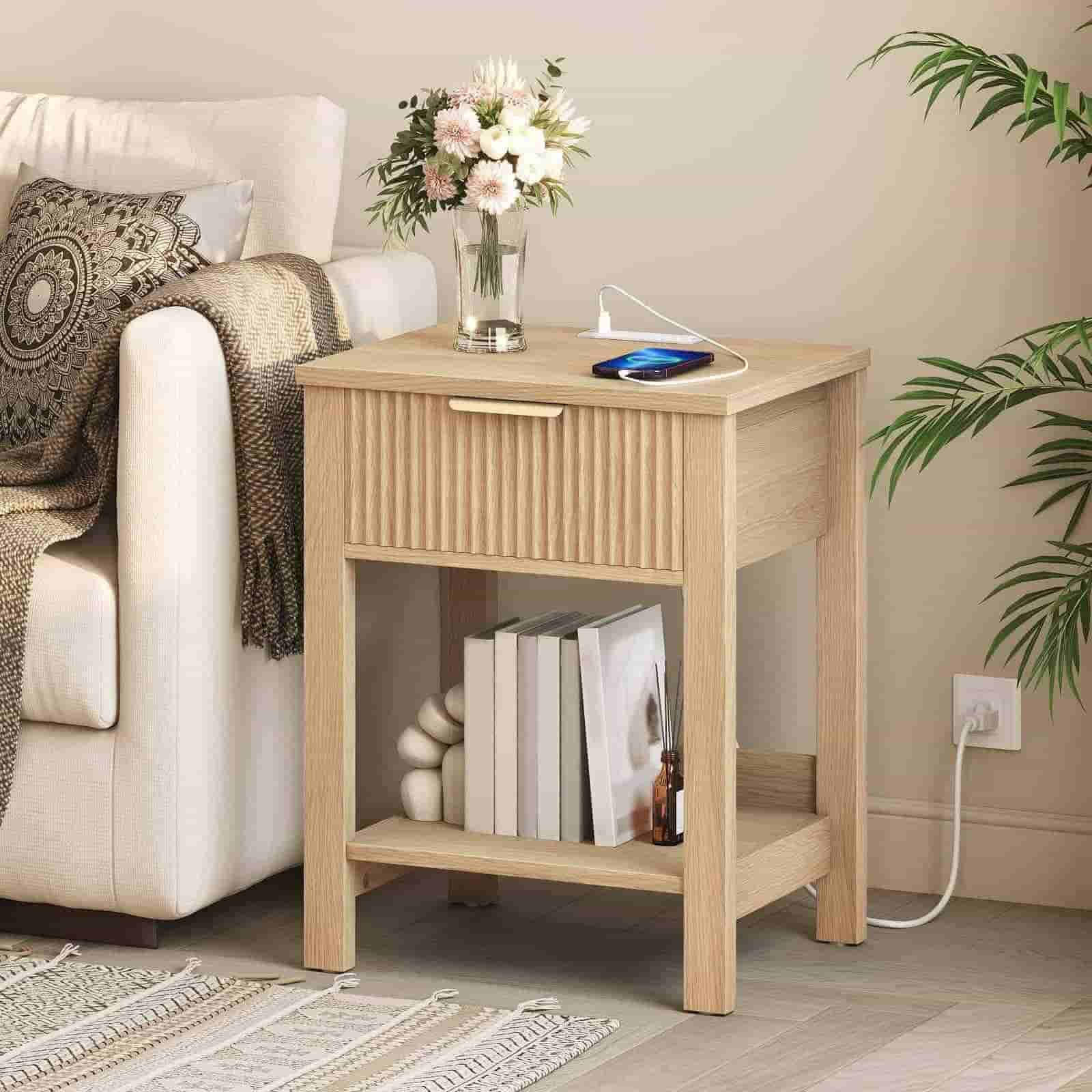Wooden side table with a lamp, books, and a vase on a living room floor.
