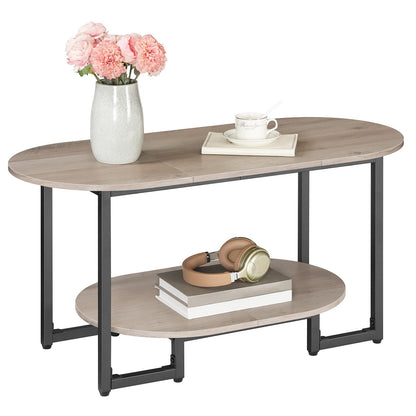 Modern oval 2-tier greige wood coffee table with black metal frame holding a flower vase and books.