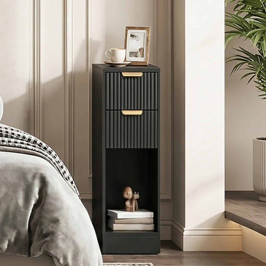 Ultra-slim black fluted nightstand with gold handles placed in a narrow gap next to a cozy bedroom bed.