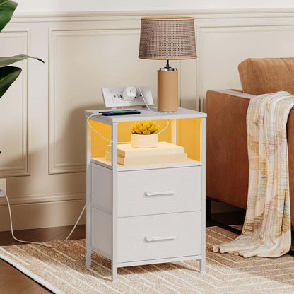 White nightstand with drawers, lamp, and phone in a bedroom setting.
