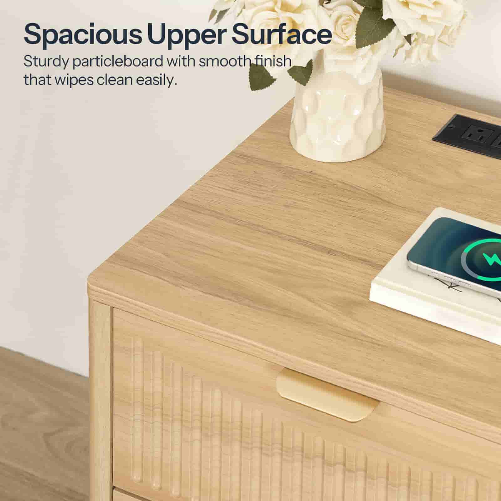 Close-up of the nightstand's upper surface showing a built-in power strip with AC outlets and USB ports charging a phone.