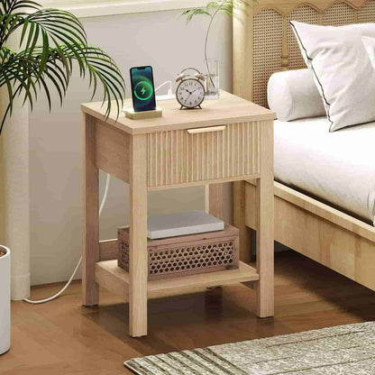 Wooden nightstand with phone, clock, and laptop next to a bed