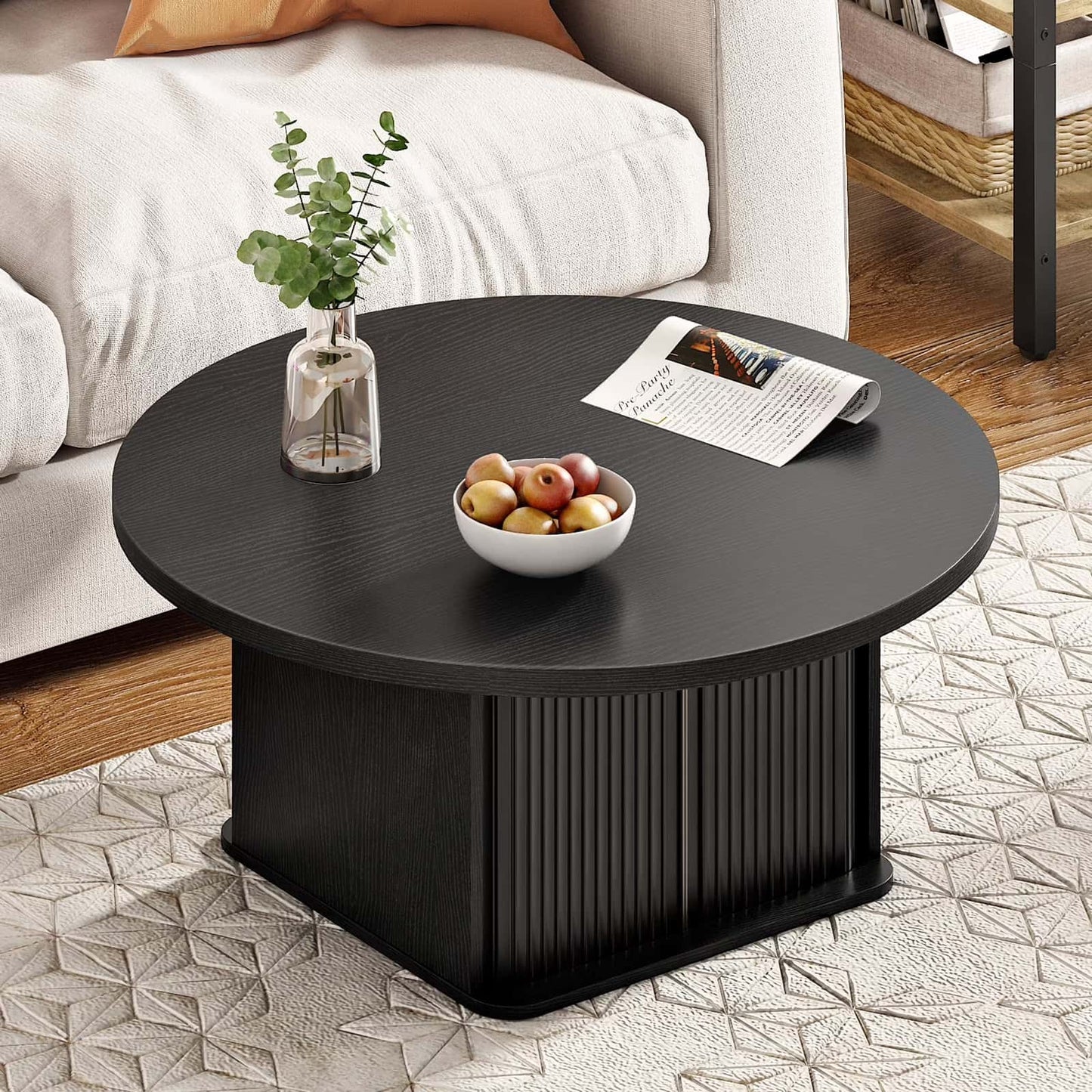 Top down view of a black round center table decorated with a fruit bowl and books.