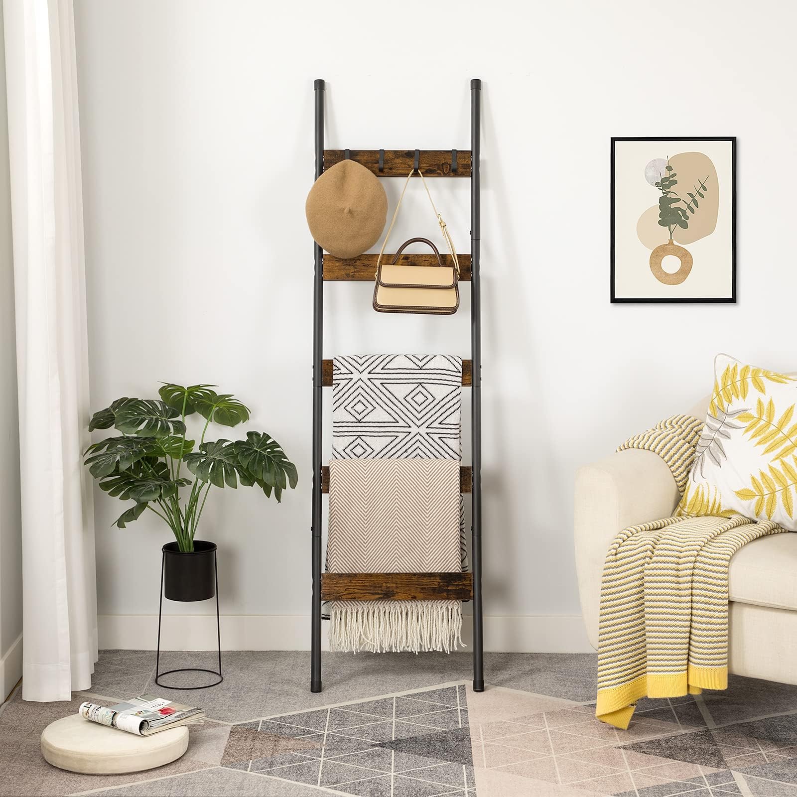 Rustic brown blanket ladder shelf leaning against a living room wall holding throws, a hat, and a handbag.
