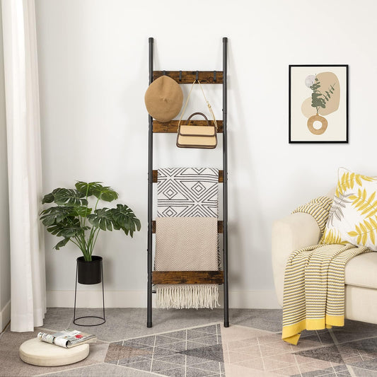 Rustic brown blanket ladder shelf leaning against a living room wall holding throws, a hat, and a handbag.