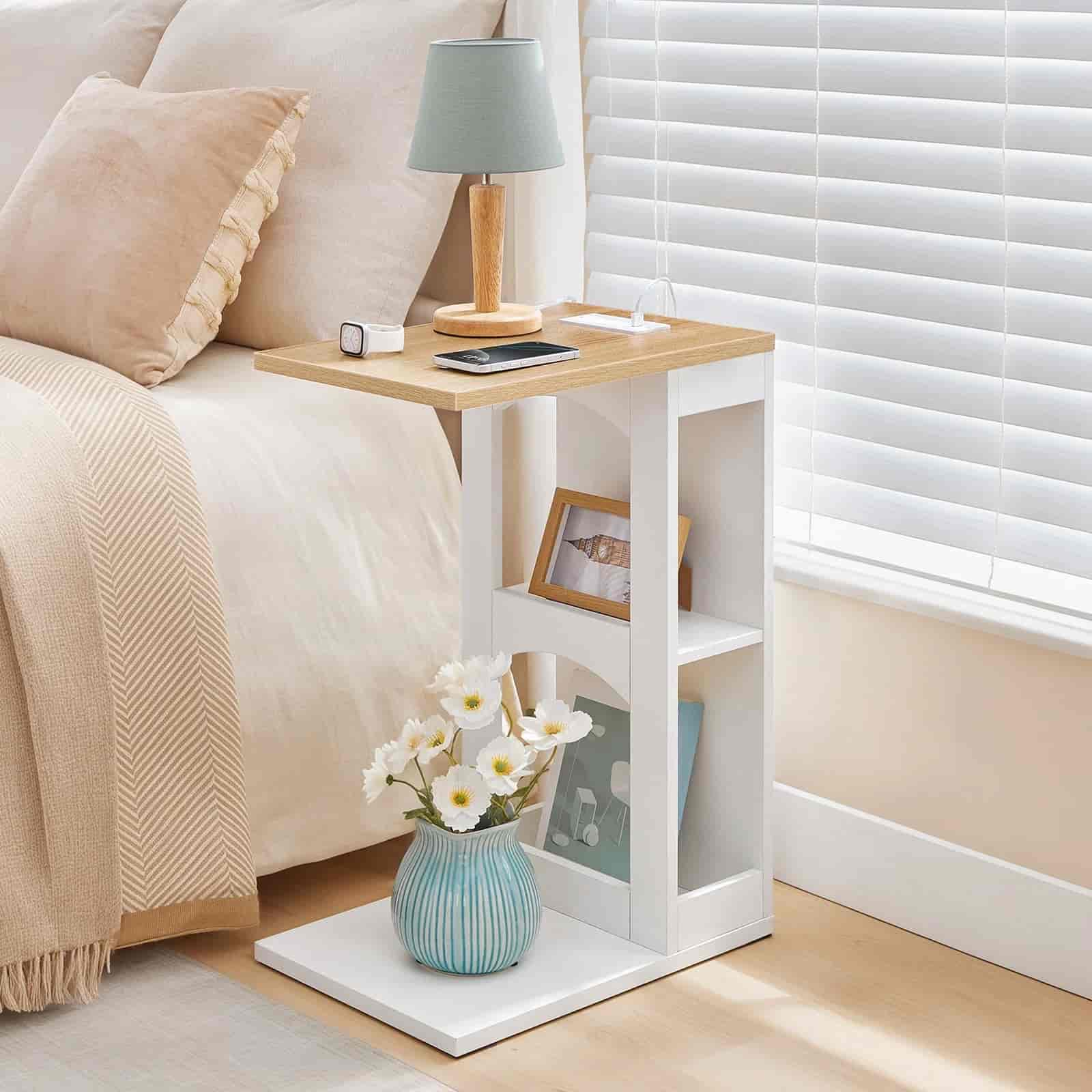 White nightstand with wooden top next to a bed with beige bedding.