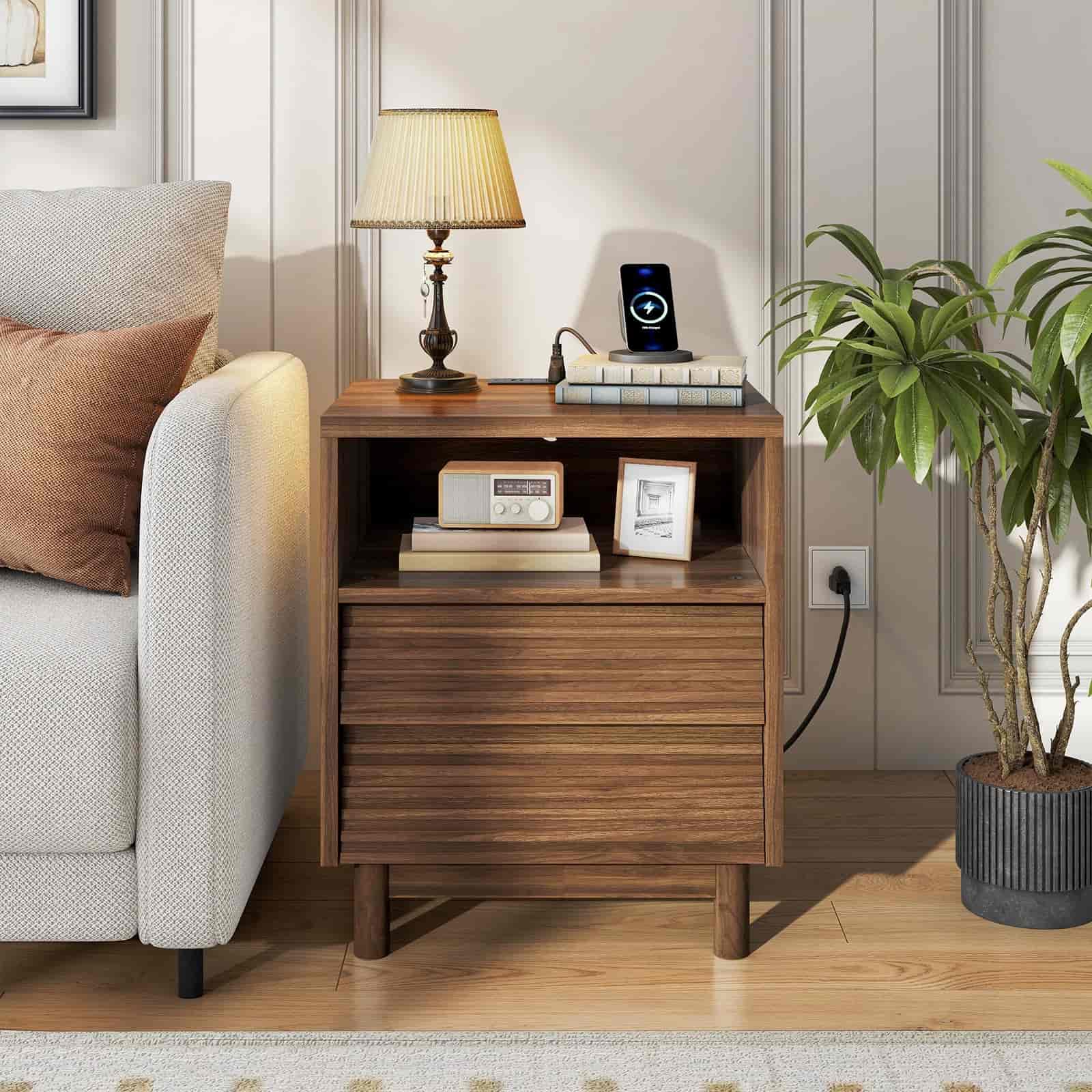 Wooden nightstand with decorative items next to a sofa in a living room setting.