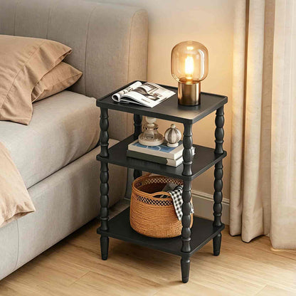 Black three-tier side table with decorative items next to a beige sofa.