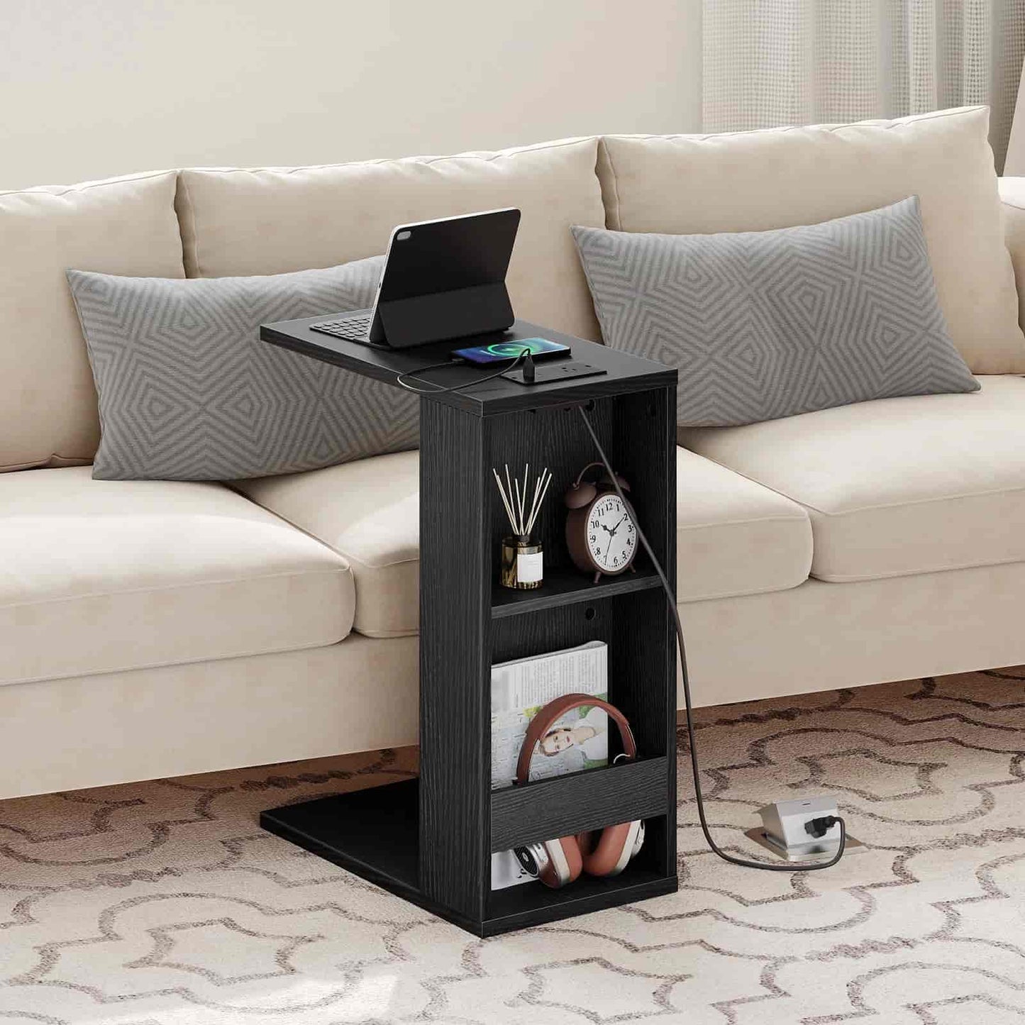 Black side table with electronic devices against a beige sofa