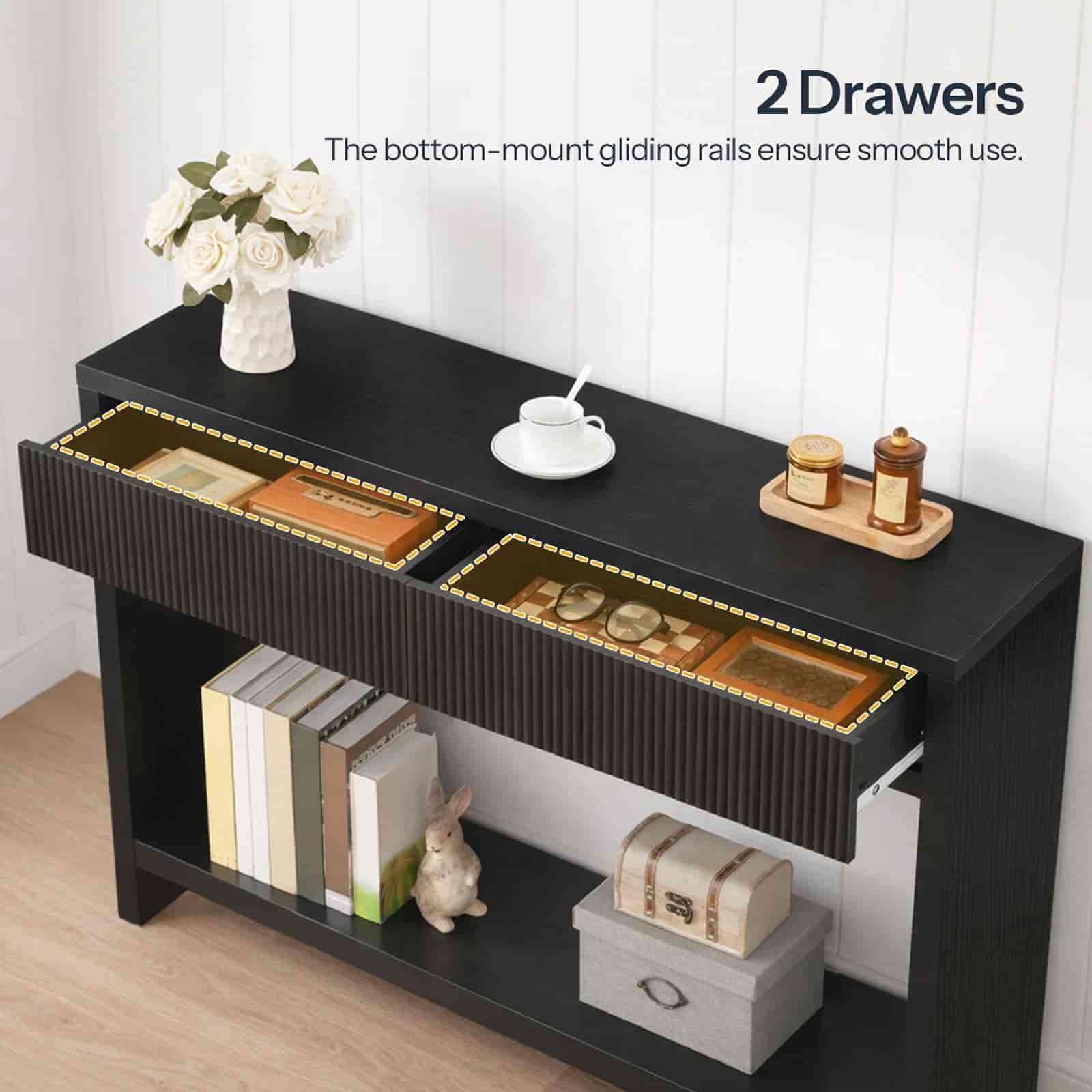 Black console table with two drawers and decorative items on a wooden floor.