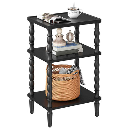 Black three-tiered side table with decorative items on a white background