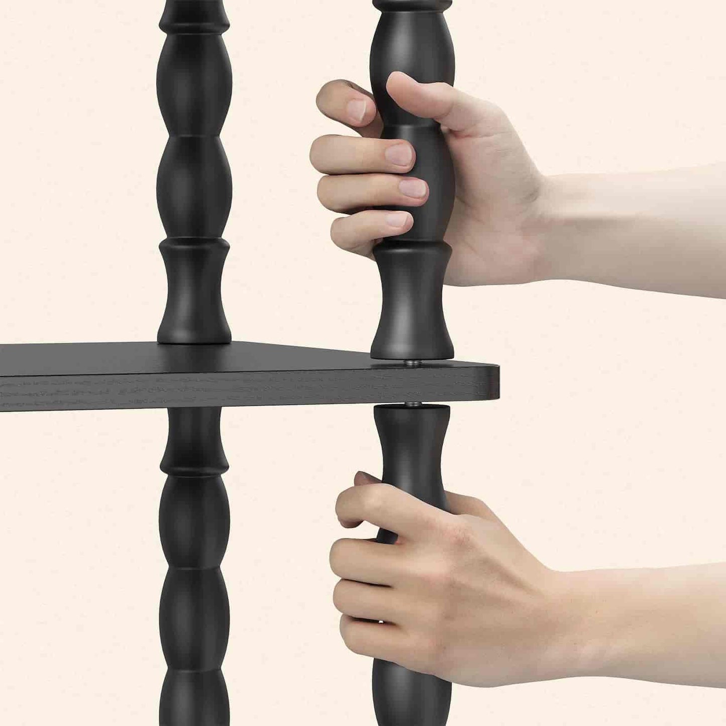 Black metal shelf with hands gripping it against a beige background