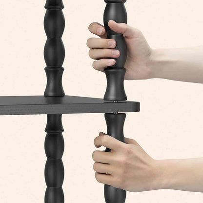 Black metal shelf with hands gripping it against a beige background