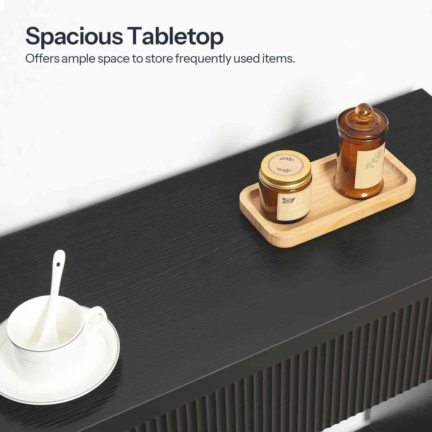 Black table with a wooden tray holding jars and a white cup with saucer.
