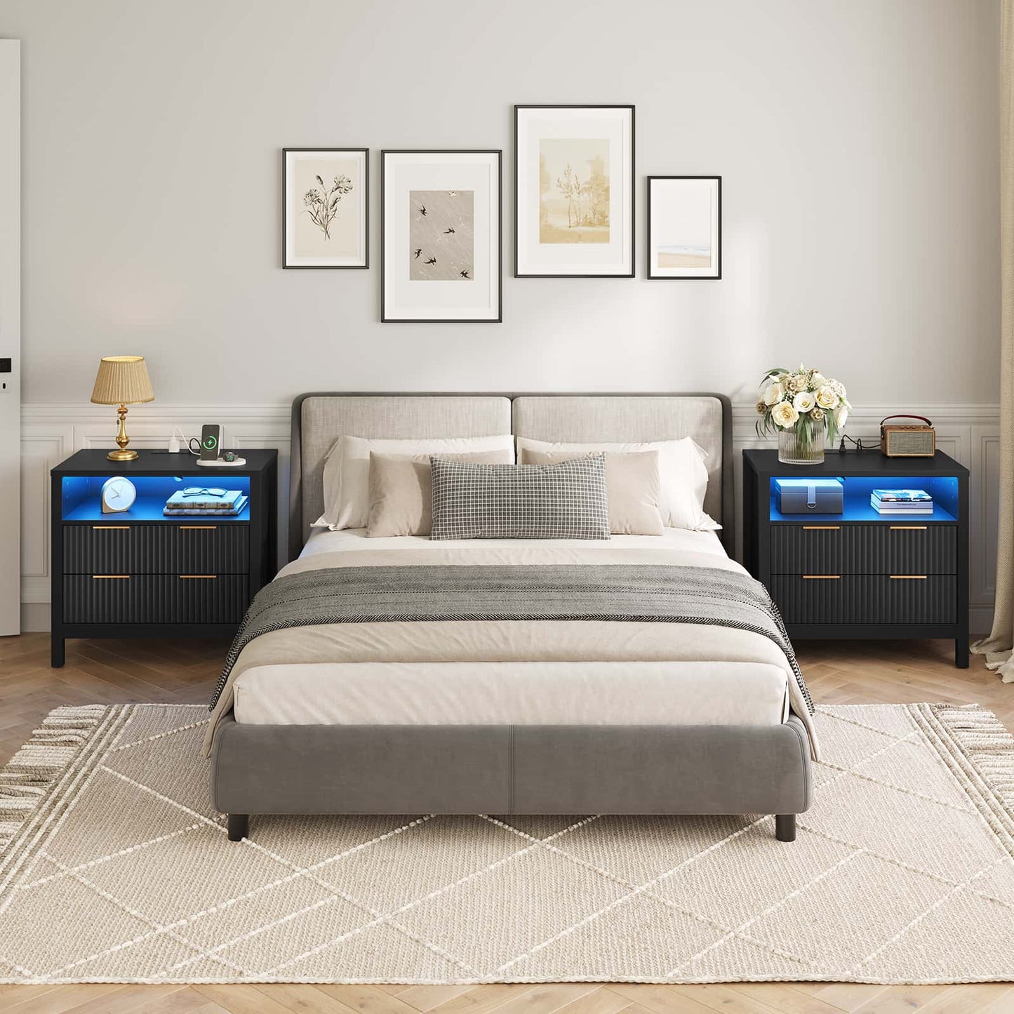 Modern bedroom with a gray upholstered bed, nightstands with LED lighting, and framed artwork on the wall.