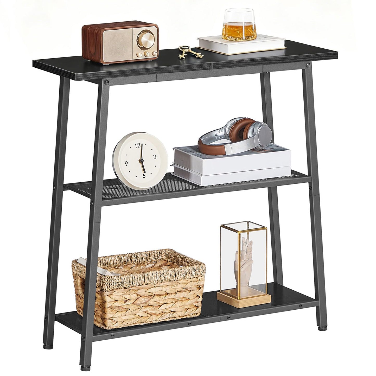 Skinny black sofa table with three storage tiers holding a vintage radio, books, and a woven basket on white background.
