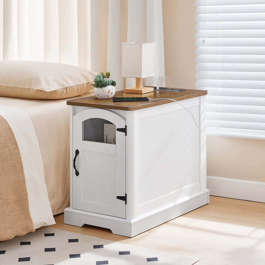 White nightstand with wooden top next to a bed in a bedroom.