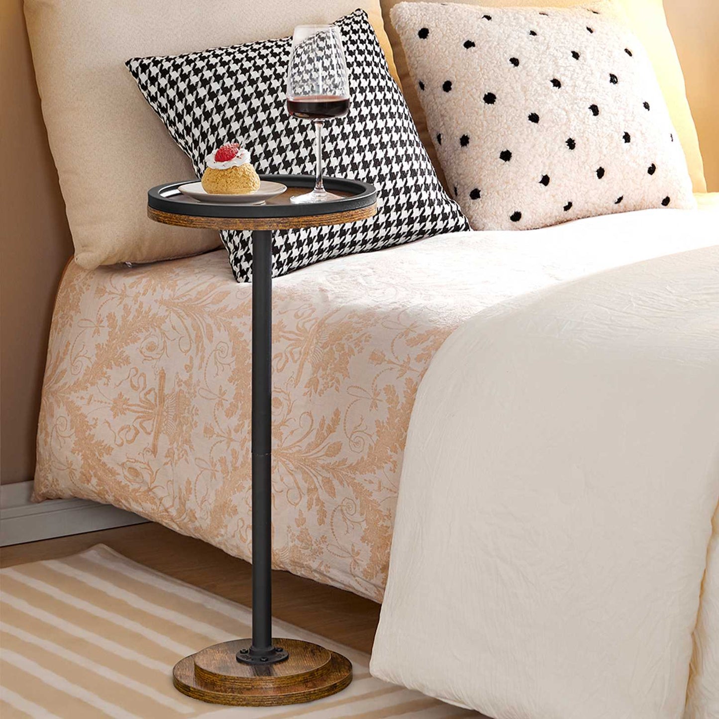 Space-saving tall round nightstand sliding right next to a bed holding candles in a bedroom.
