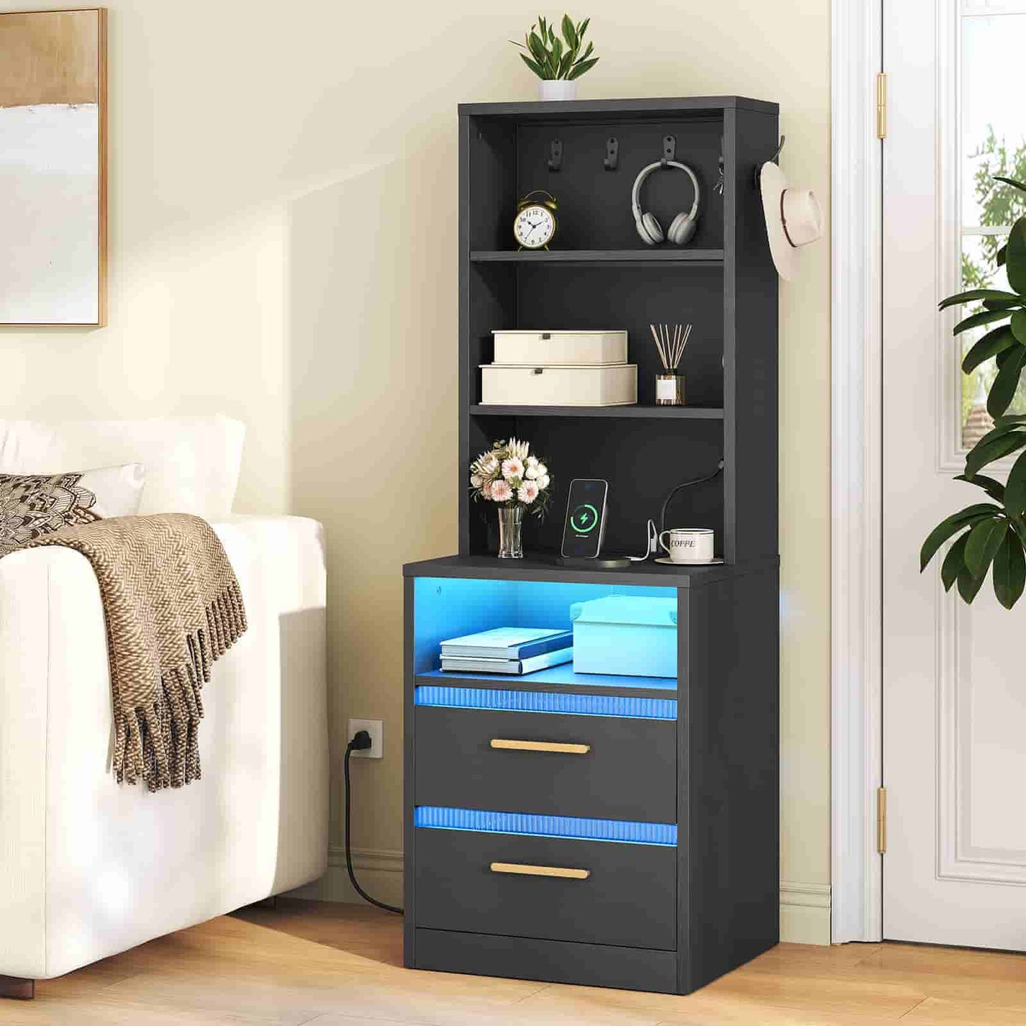 Sleek black tall accent table placed next to a beige bed, beautifully styled with books, headphones, and home decor.
