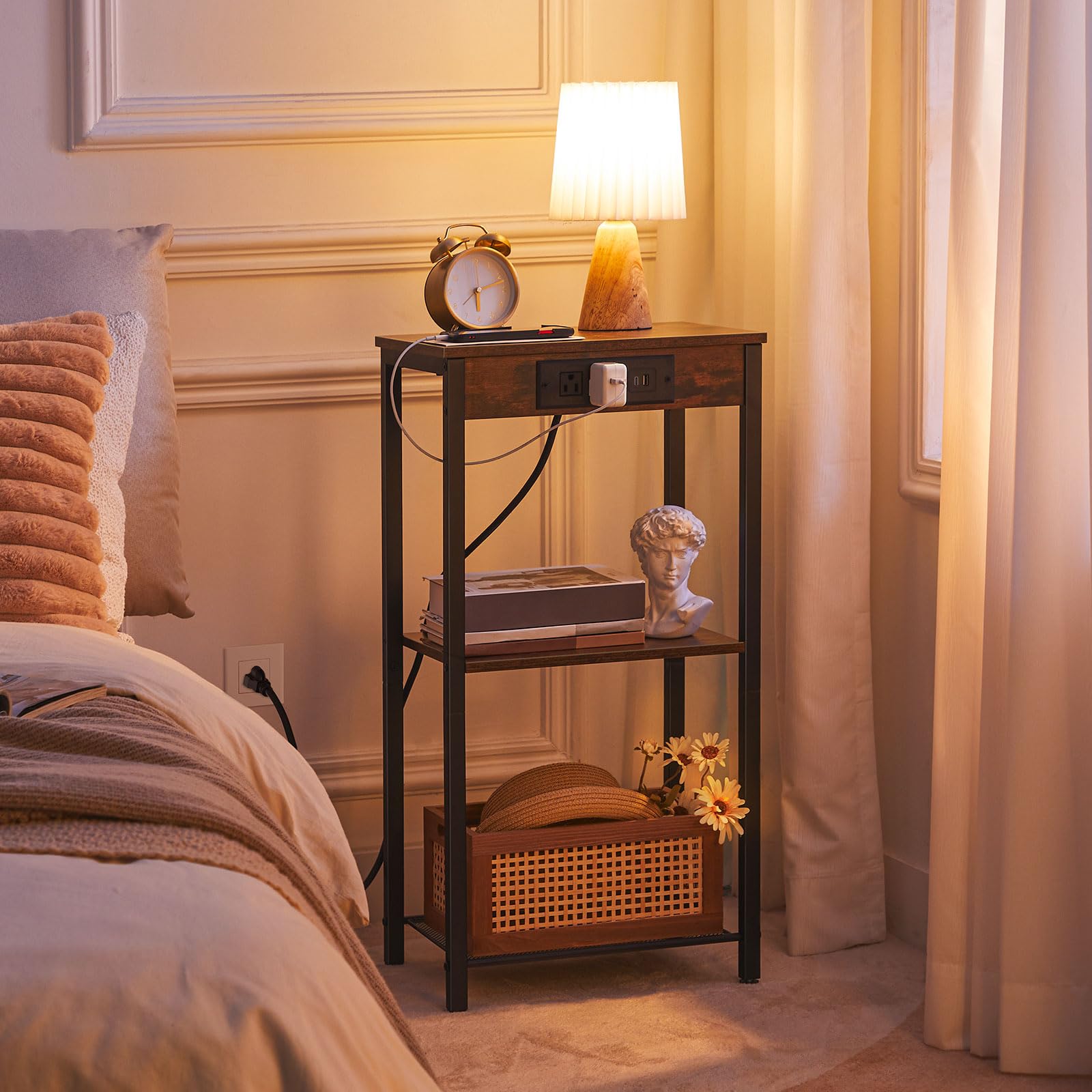 Tall bedside nightstand with warm lamp light glowing next to a bed in a cozy bedroom.