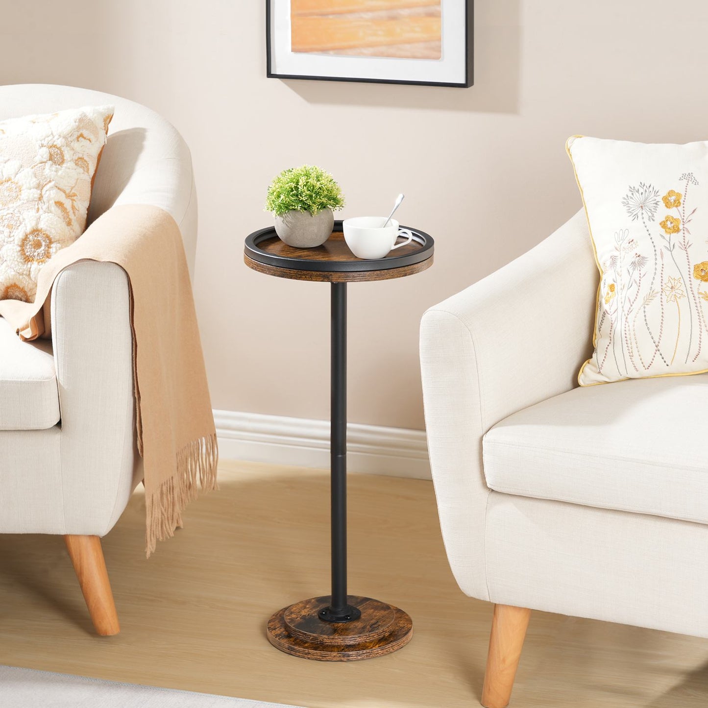 Rustic brown tall round side table with a tray top styled between two white living room armchairs.