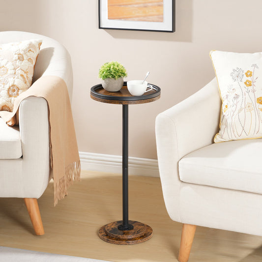 Rustic brown tall round side table with a tray top styled between two white living room armchairs.