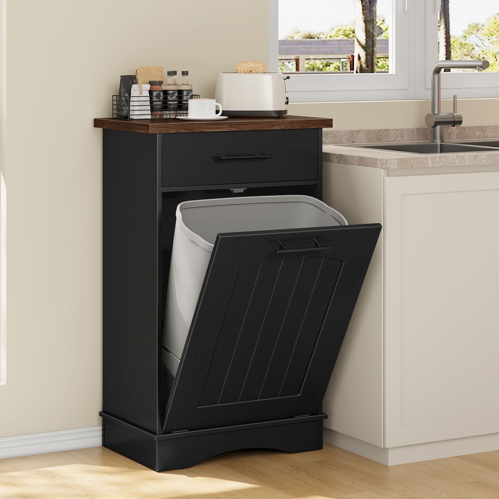 Tilt-out storage cabinet used as a hidden trash recycling station next to a kitchen counter sink.