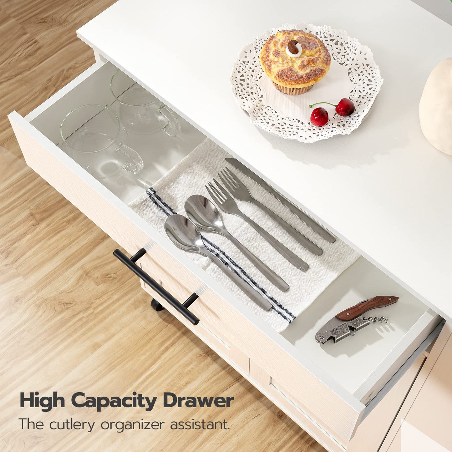 Open kitchen drawer with cutlery organizer and a cupcake on a wooden surface